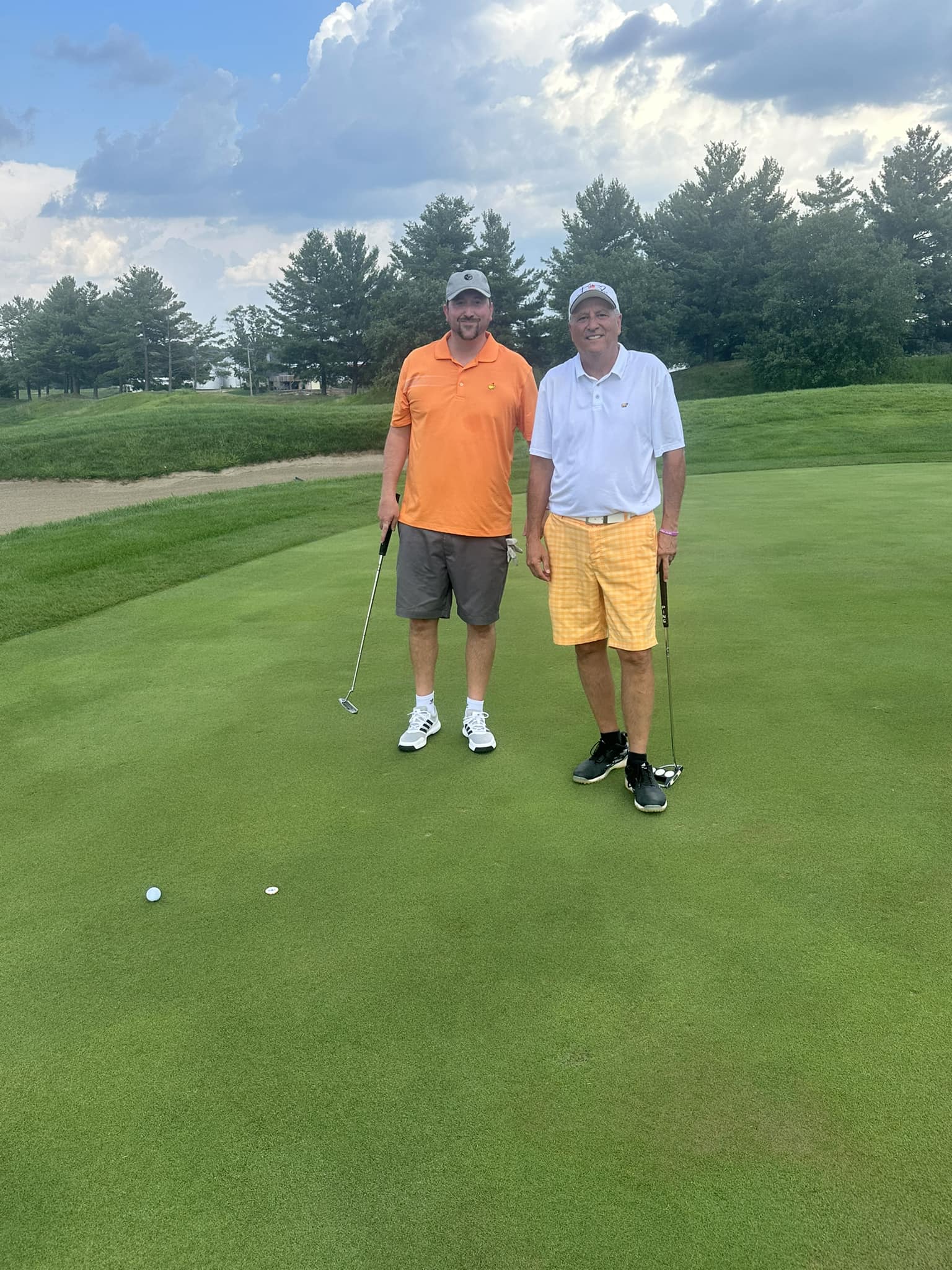 Two golfers smiling at the camera ready to play golf.