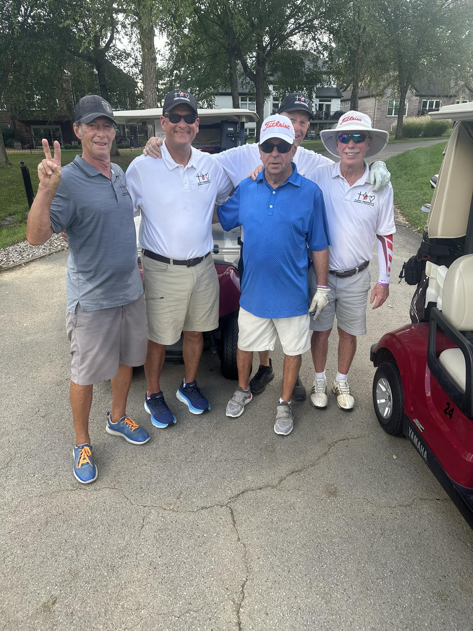 A group of golfers smiling together and holding their clubs.