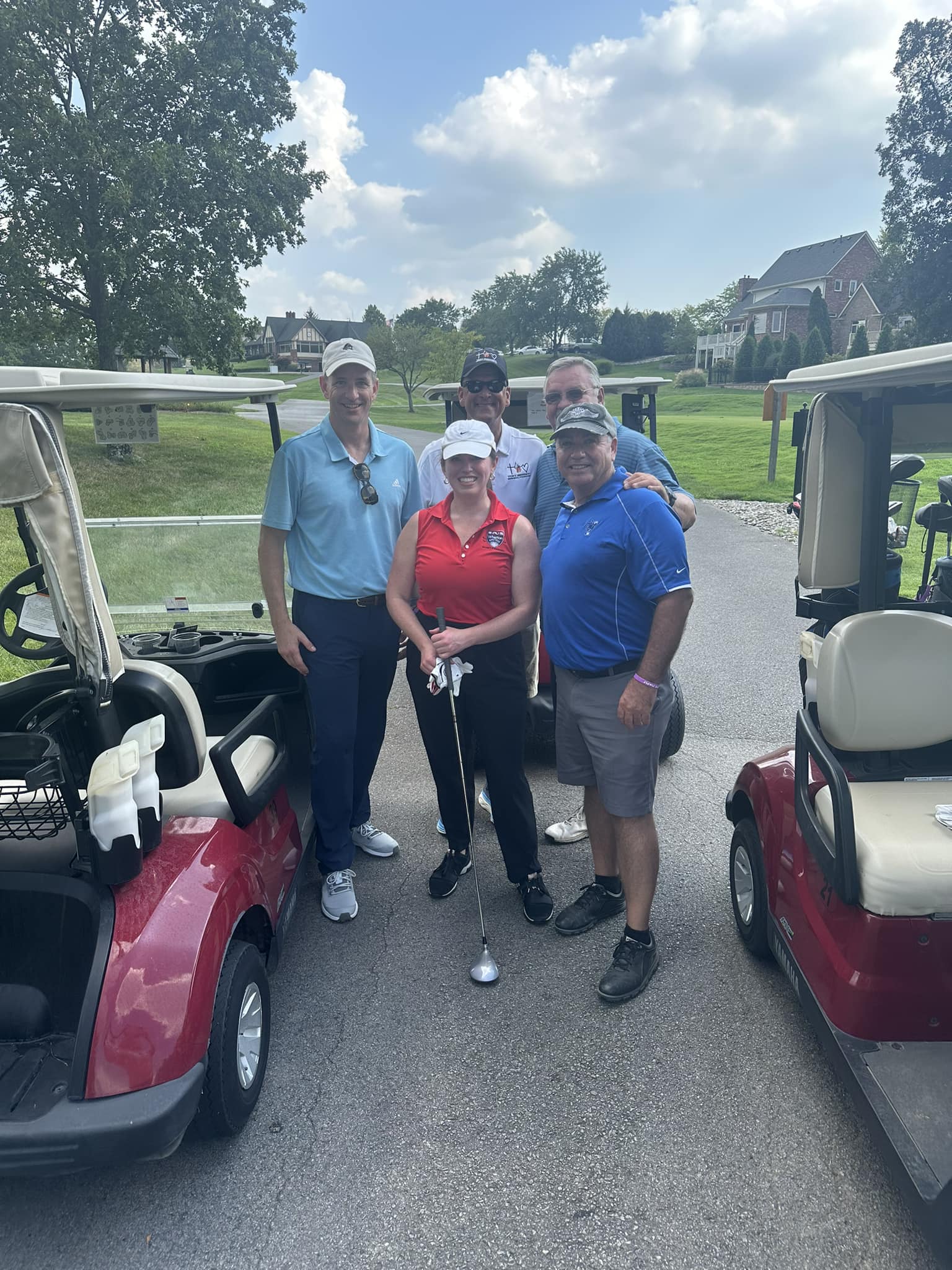A group of golfers smiling together and holding their clubs.