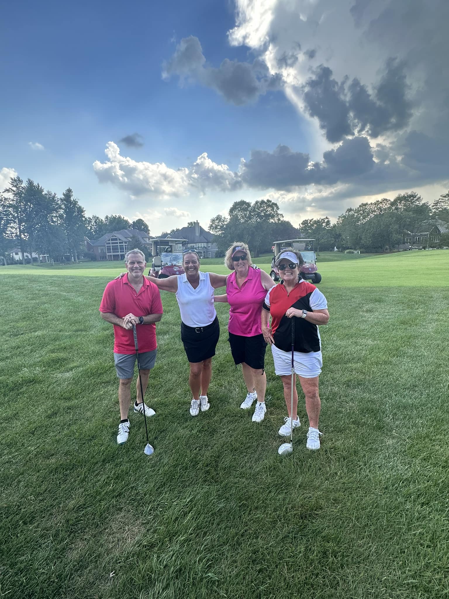 A group of golfers smiling together and holding their clubs.