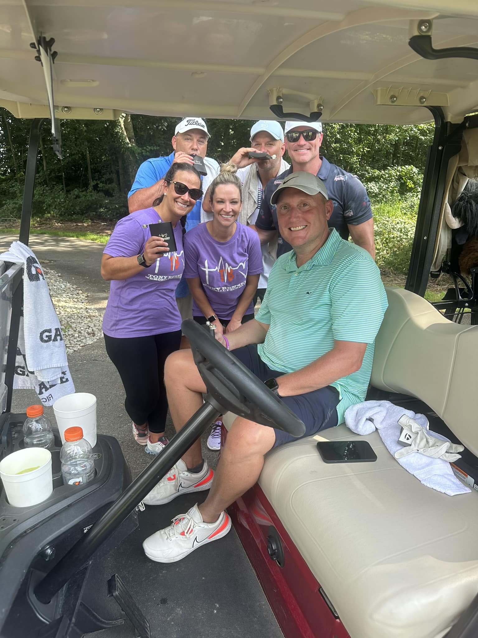 A group of golfers smiling together and holding their clubs.