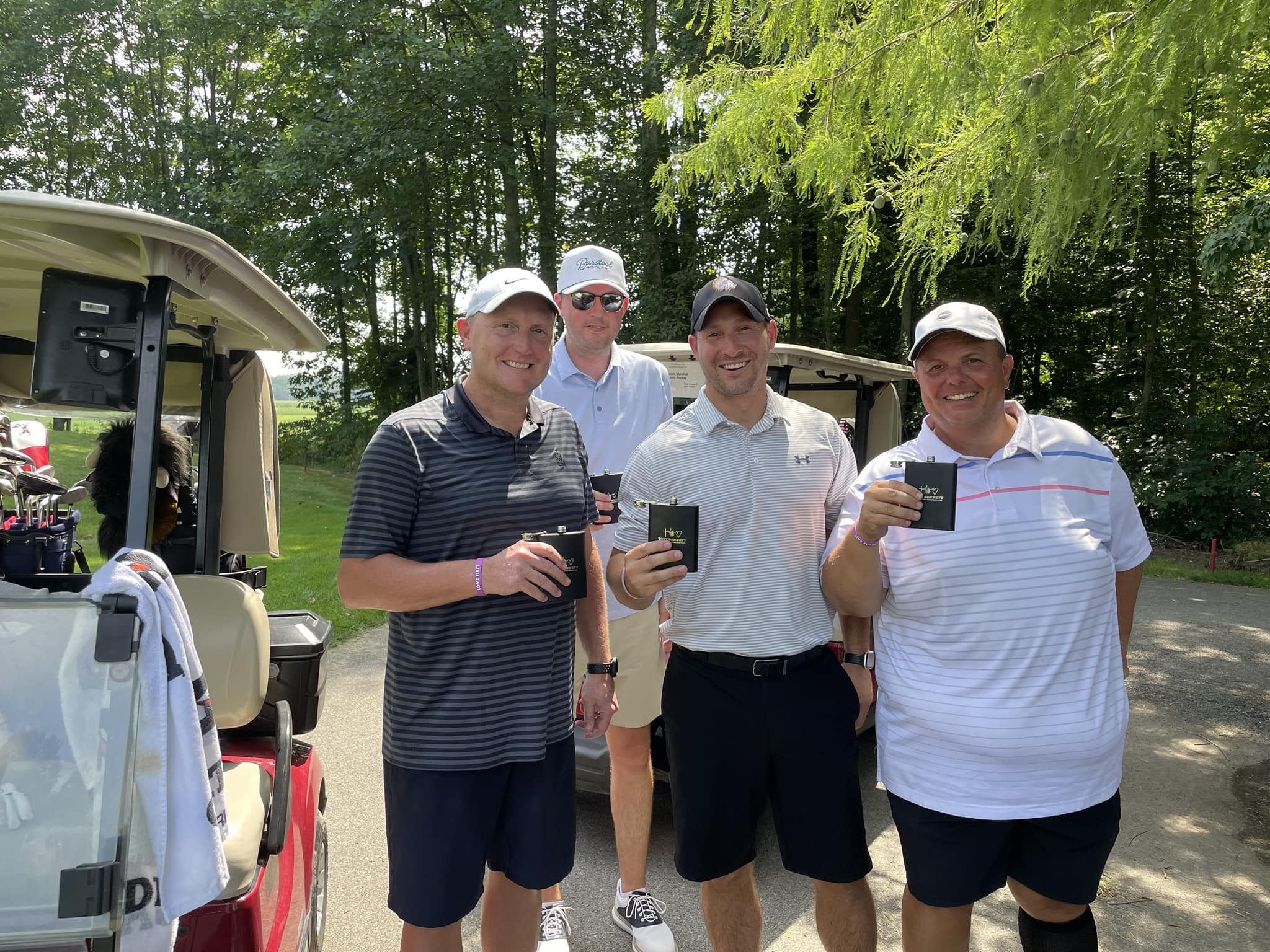 A group of golfers smiling together and holding their clubs.
