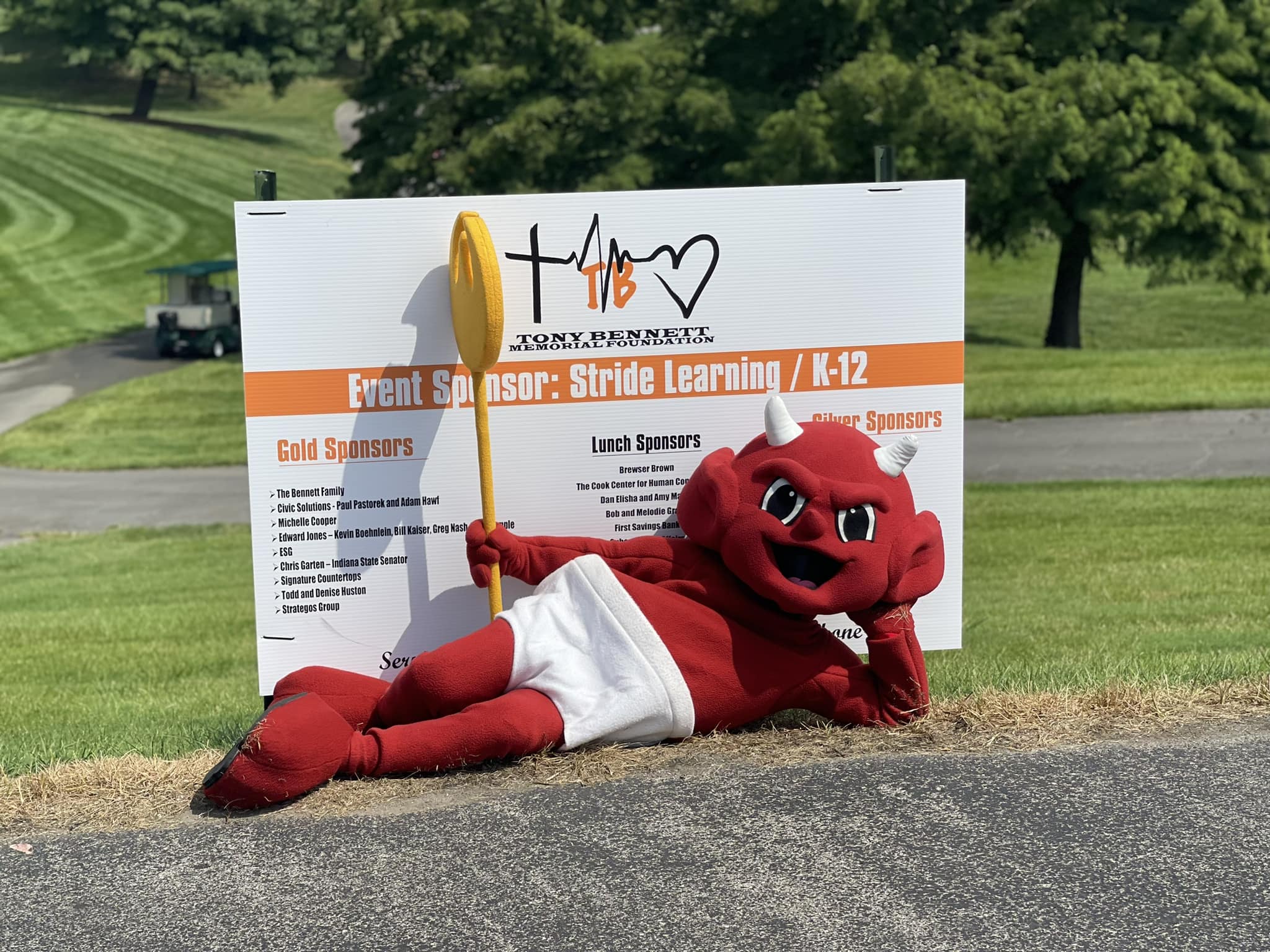 Restaurant, Torchy's Tacos, mascot, the red devil, laying infront of a sponsor sign.
