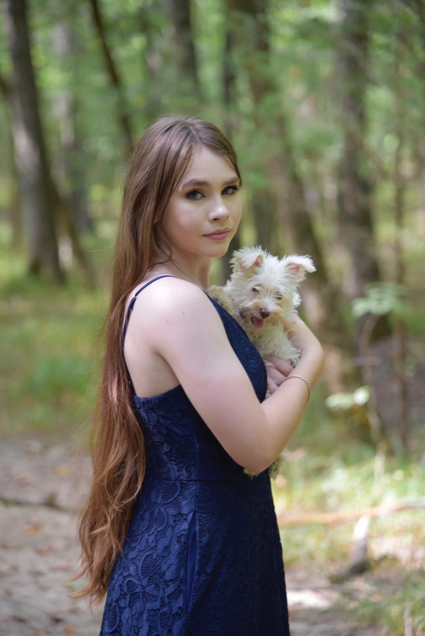 Hannah Ghidotti in a blue dress holding a white dog