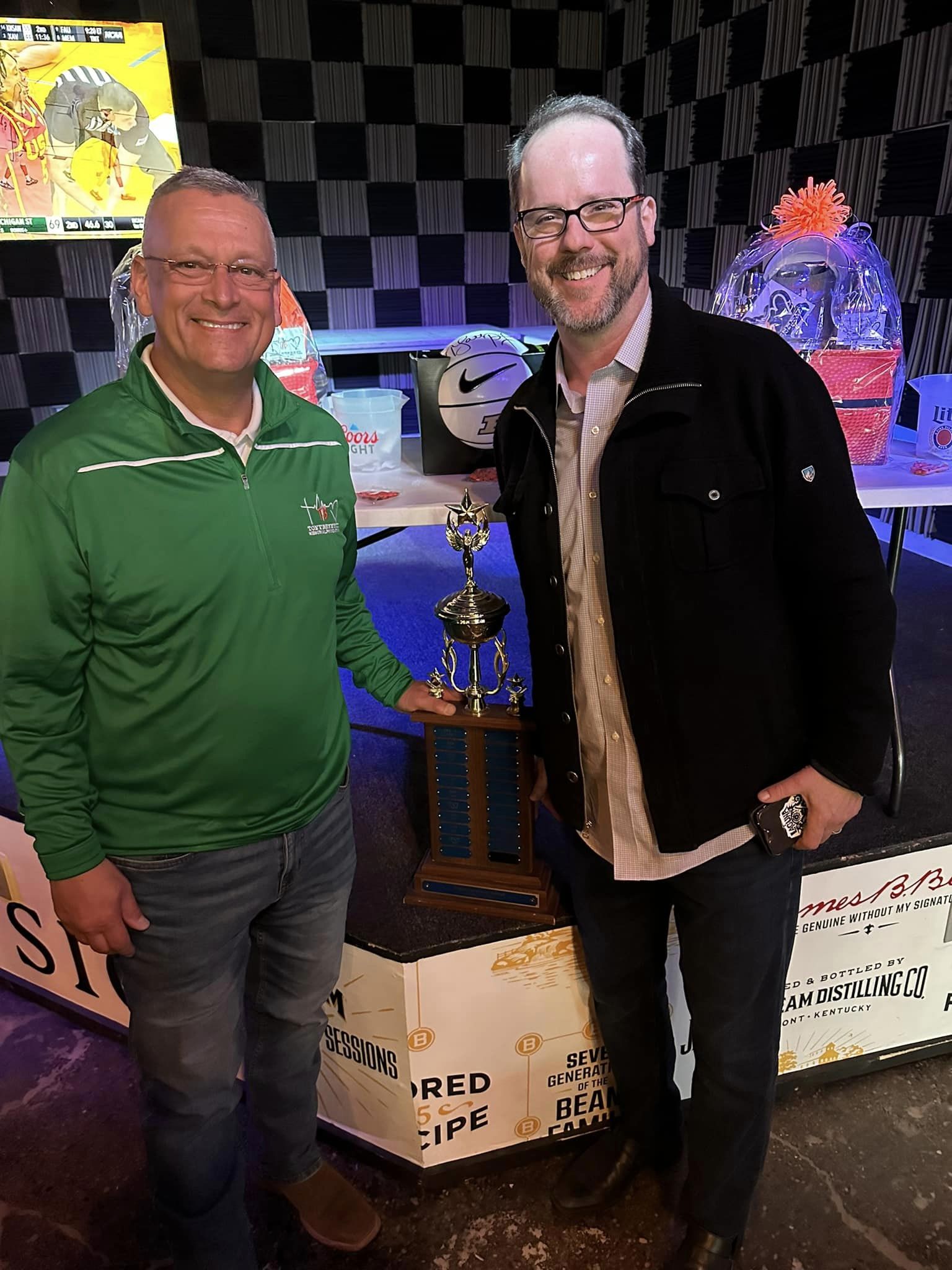 Two men with a trophy in between them