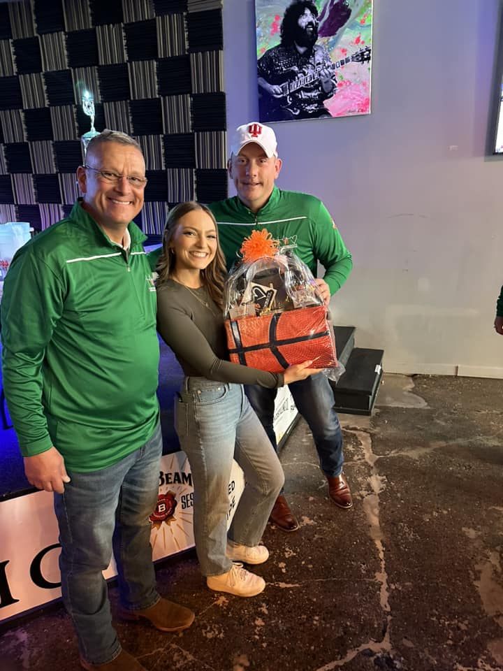 Two men and a woman posing with a gift basket